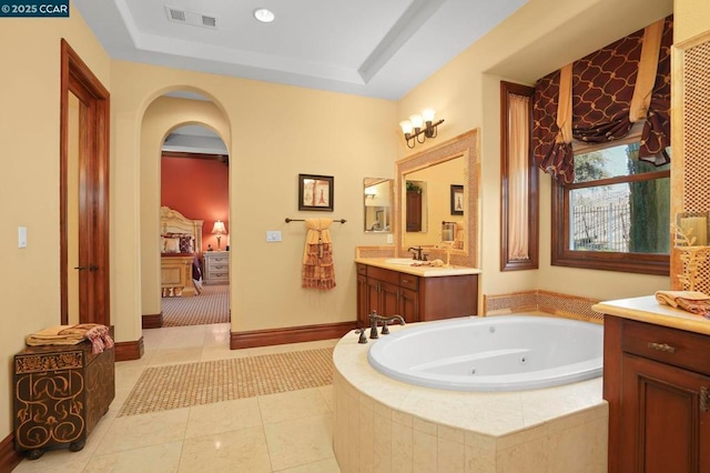 bathroom with tile patterned flooring, a relaxing tiled tub, a raised ceiling, and vanity