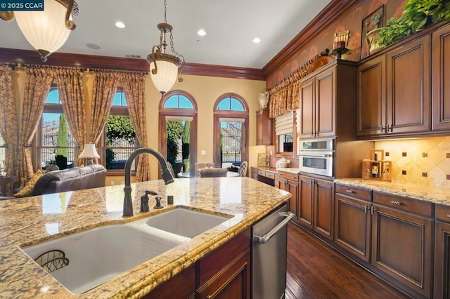 kitchen with sink, hanging light fixtures, light stone countertops, stainless steel appliances, and ornamental molding