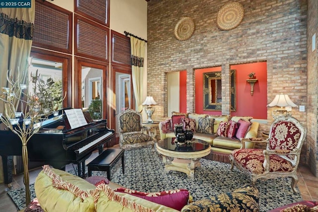 living room featuring tile patterned floors, brick wall, and a towering ceiling