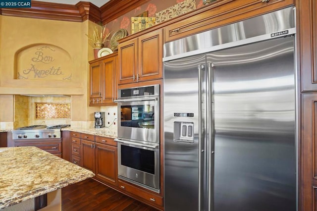 kitchen with dark wood-type flooring, light stone countertops, appliances with stainless steel finishes, and crown molding