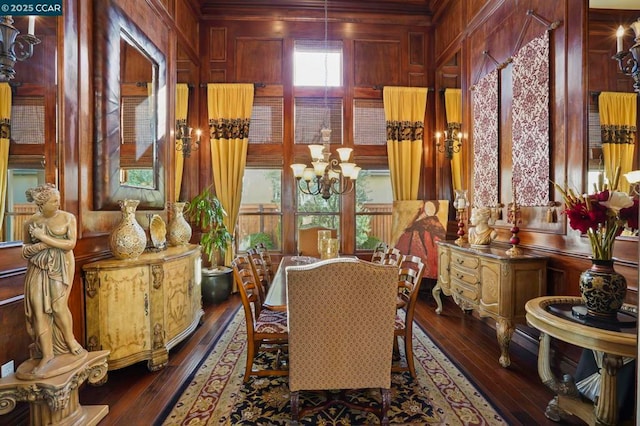 dining area featuring dark hardwood / wood-style floors, wood walls, and an inviting chandelier