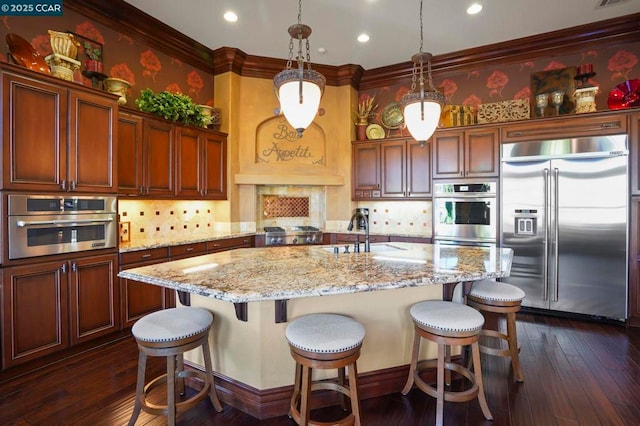 kitchen featuring a center island with sink, stainless steel appliances, tasteful backsplash, pendant lighting, and sink