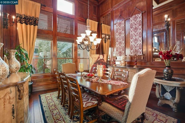 dining space with dark hardwood / wood-style floors, a chandelier, and wood walls