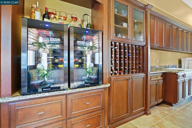 bar featuring light tile patterned flooring, beverage cooler, and light stone countertops