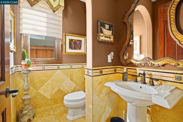 bathroom featuring toilet, tile walls, and tile patterned floors