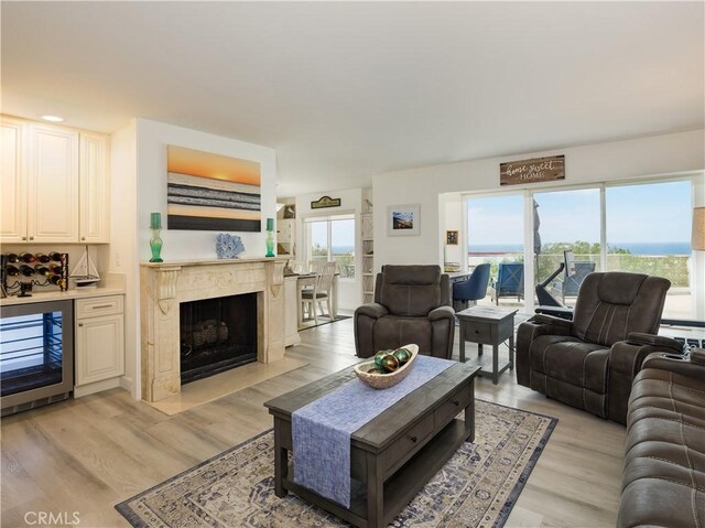 living room featuring a high end fireplace, wine cooler, and light hardwood / wood-style floors