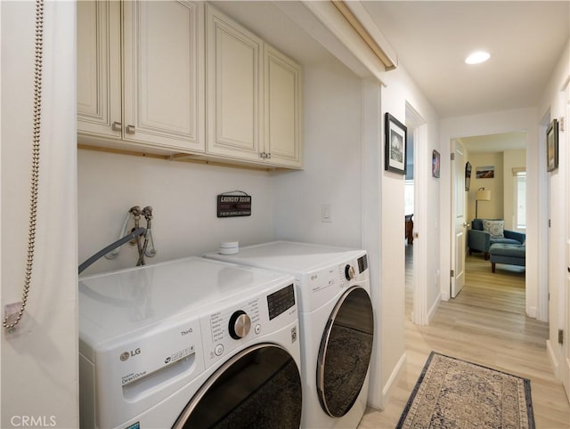 clothes washing area with cabinets, independent washer and dryer, and light hardwood / wood-style flooring