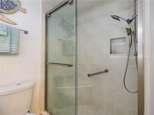 bathroom featuring toilet and a shower with door