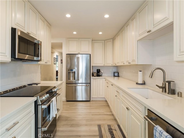 kitchen with sink, white cabinetry, stainless steel appliances, and tasteful backsplash