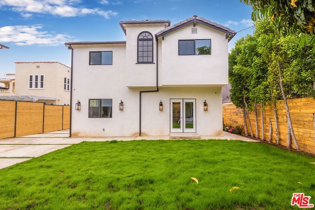 back of house with french doors and a lawn