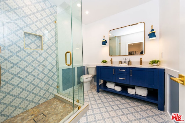 bathroom featuring a shower with shower door, toilet, and vanity