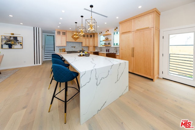 kitchen with a healthy amount of sunlight, light wood-type flooring, light stone countertops, and a center island