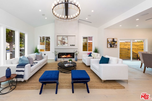 living room featuring an inviting chandelier, lofted ceiling, and light hardwood / wood-style floors