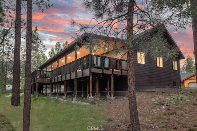 back house at dusk featuring a wooden deck