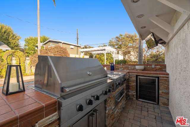 view of patio / terrace with wine cooler, exterior kitchen, a pergola, and area for grilling