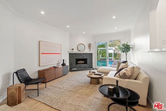 living room featuring ornamental molding, light hardwood / wood-style flooring, and a stone fireplace