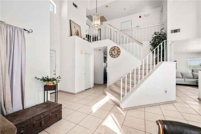 entryway with a towering ceiling and light tile patterned flooring