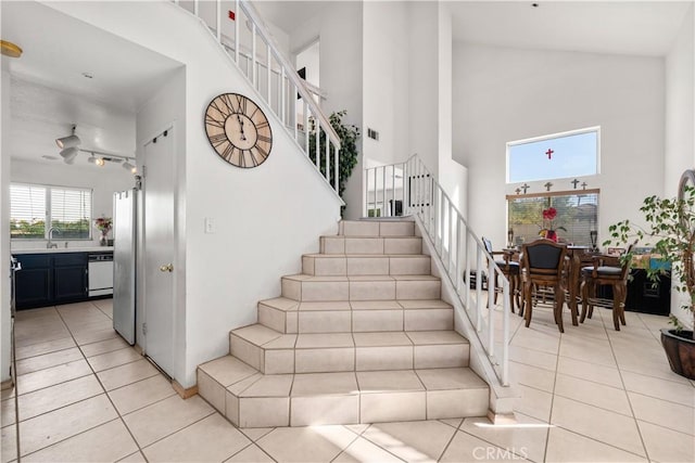 stairs with sink, tile patterned floors, and a towering ceiling