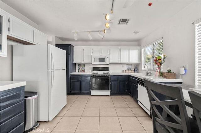 kitchen featuring sink, light tile patterned flooring, white appliances, and white cabinetry