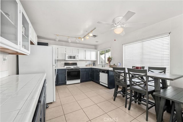 kitchen with light tile patterned floors, ceiling fan, tile counters, white appliances, and white cabinets