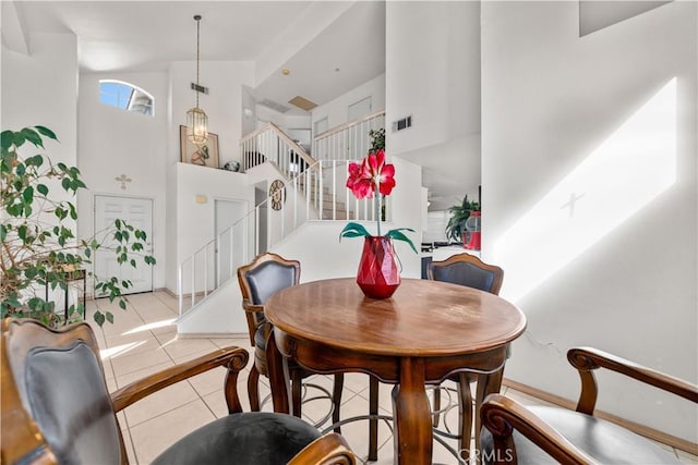 dining room with light tile patterned floors and a high ceiling