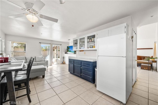 kitchen with ceiling fan, blue cabinetry, white refrigerator, and white cabinetry