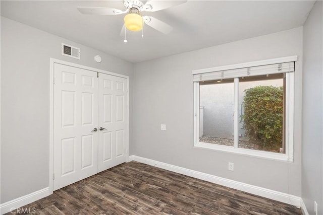 unfurnished bedroom with dark wood-type flooring, a closet, and ceiling fan