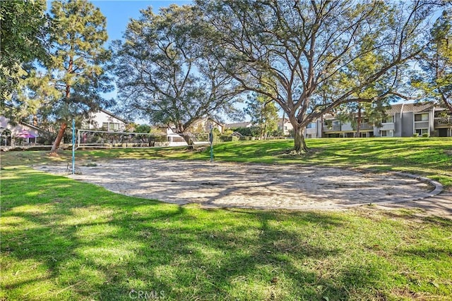 view of property's community with a lawn and volleyball court