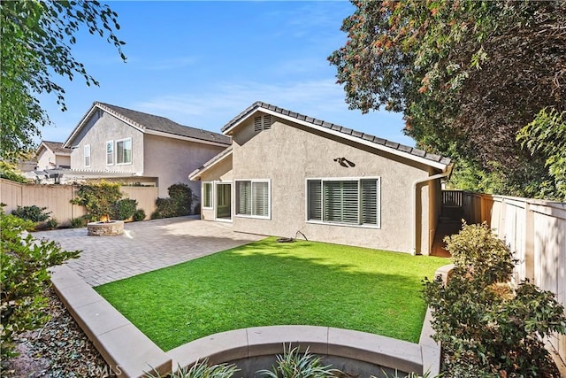 back of house featuring a yard, a fire pit, and a patio