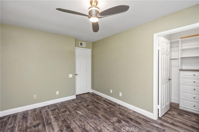 unfurnished bedroom featuring ceiling fan, dark hardwood / wood-style floors, a closet, and a walk in closet