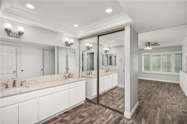 bathroom with ceiling fan, vanity, hardwood / wood-style floors, a raised ceiling, and ornamental molding