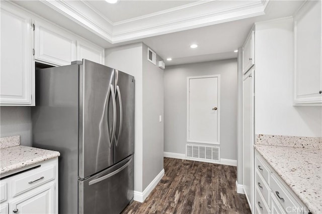 kitchen with light stone countertops, white cabinets, dark wood-type flooring, stainless steel refrigerator, and crown molding