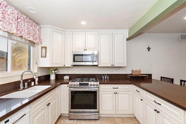 kitchen with white cabinets, stainless steel appliances, sink, kitchen peninsula, and light tile patterned flooring