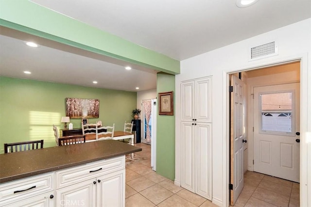 kitchen with light tile patterned floors, white cabinetry, and dark stone counters