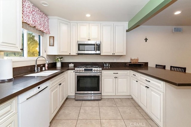 kitchen with appliances with stainless steel finishes, white cabinets, and kitchen peninsula