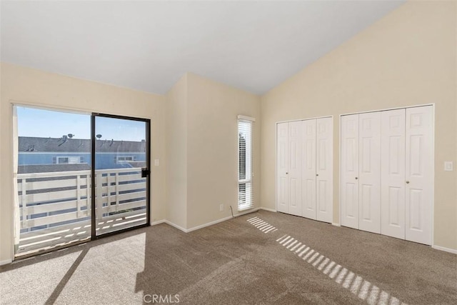 unfurnished bedroom with baseboards, lofted ceiling, access to exterior, carpet flooring, and two closets