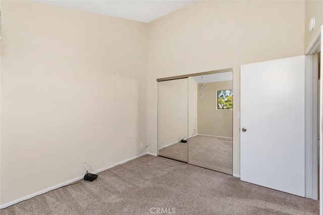 unfurnished bedroom featuring a closet, baseboards, carpet, and a high ceiling