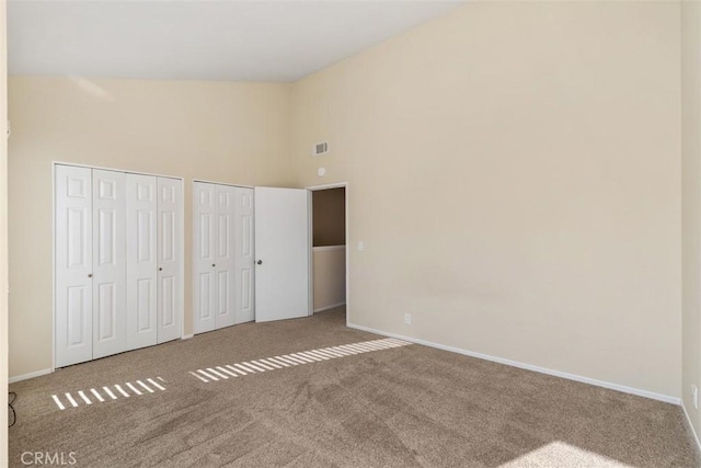 unfurnished bedroom featuring visible vents, carpet, multiple closets, and baseboards