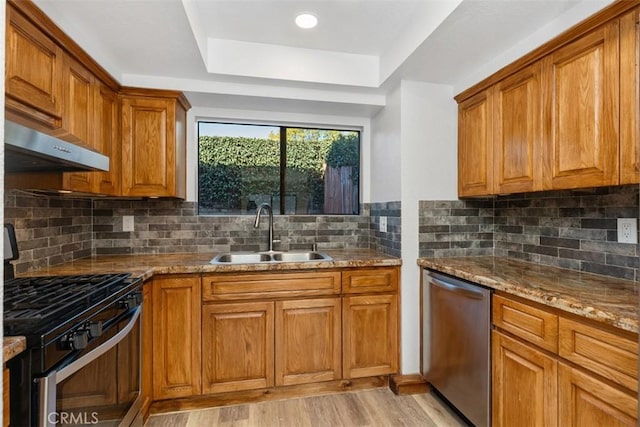 33611 Dana Vista Dr Unit 31, Dana Point, CA 92629 - kitchen with stainless steel appliances, range hood, brown cabinetry, a tray ceiling, and light wood-style floors