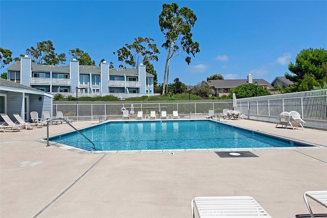 community pool with a patio area and fence