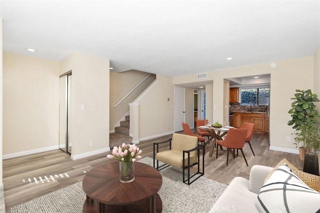 living area featuring visible vents, stairway, baseboards, and light wood-type flooring