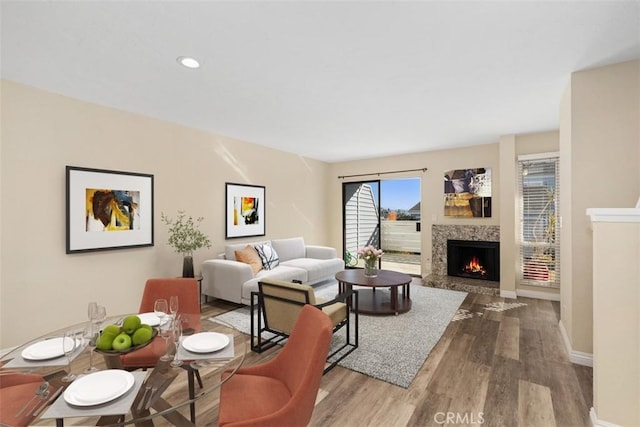 living room with recessed lighting, baseboards, a lit fireplace, and wood finished floors