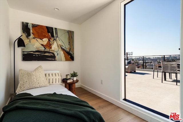 bedroom featuring multiple windows, wood-type flooring, and radiator heating unit