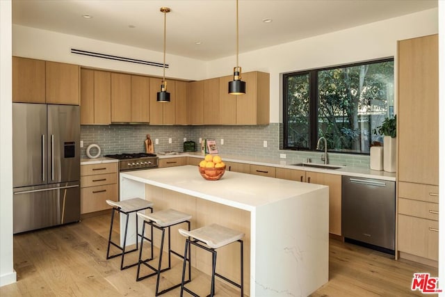 kitchen with tasteful backsplash, sink, hanging light fixtures, a kitchen breakfast bar, and stainless steel appliances