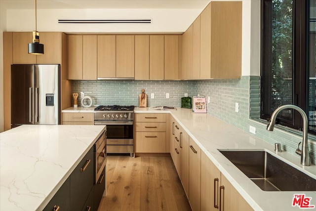 kitchen featuring decorative light fixtures, decorative backsplash, sink, light brown cabinetry, and high quality appliances