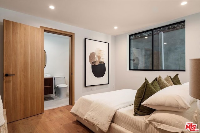 bedroom with connected bathroom and light hardwood / wood-style flooring