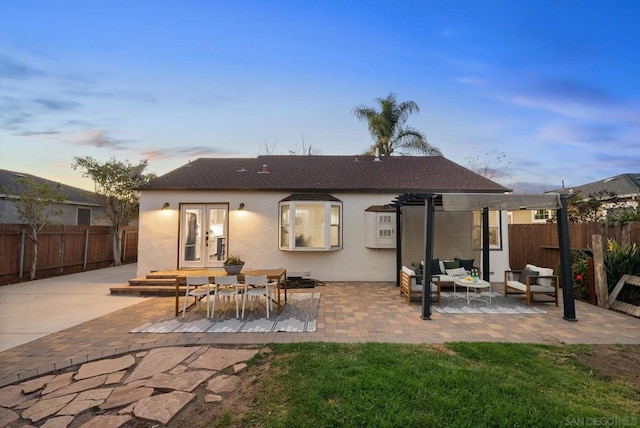 back house at dusk with outdoor lounge area, french doors, and a patio