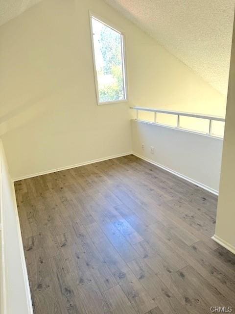 additional living space with a textured ceiling, lofted ceiling, and dark hardwood / wood-style floors