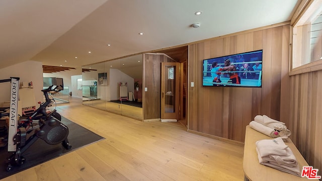 exercise room with vaulted ceiling, hardwood / wood-style floors, and wood walls