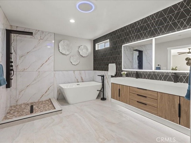 bathroom featuring ceiling fan, tile walls, vanity, and independent shower and bath